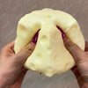 A hand is squeezing a large, pale yellow cheese cube stress ball.