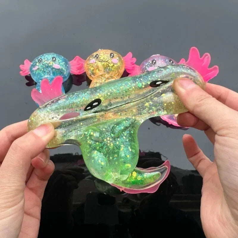 A hand holds a translucent, squishy axolotl stress relief toy with pink and yellow accents.
