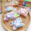 A collection of pink and blue cat paw squishy stress relief toys packaged in clear plastic bags on a woven tray.