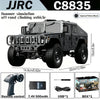 A black 1:12 scale RC off-road climbing vehicle with a remote control and accessories.