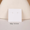A white square jewelry display card with two small holes is shown against a light beige background.