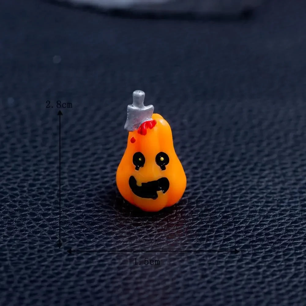 An orange cartoon pumpkin bear figurine with a white stem and red accents, displayed on a dark surface.