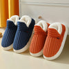 A pair of women's cozy faux fur slippers in navy blue and orange are displayed on a white surface.