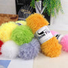 A collection of bright yellow, green, purple, and orange chunky faux fur yarn balls.