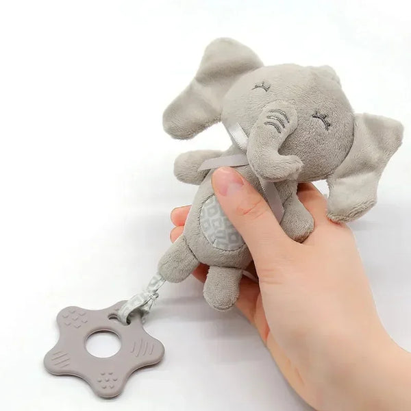 A hand is holding a gray elephant plush animal rattle designed for a baby stroller.