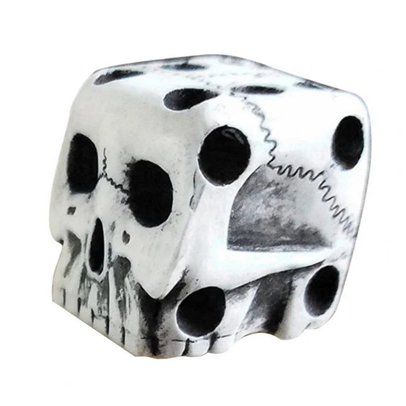 A silver-colored mini skull dice set with hollowed-out eyes and features, used for games.