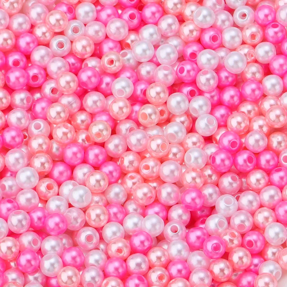 A close-up of small, colorful imitation pearl beads in shades of pink and magenta.