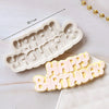 A set of white silicone cake molds shaped like a baby's face and the words Happy Birthday