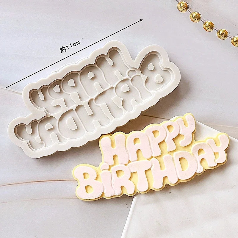 A set of white silicone cake molds shaped like a baby's face and the words Happy Birthday