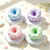 Four pastel colored squishy stress balls in various shades of blue, purple, pink, and green resting on a light background.