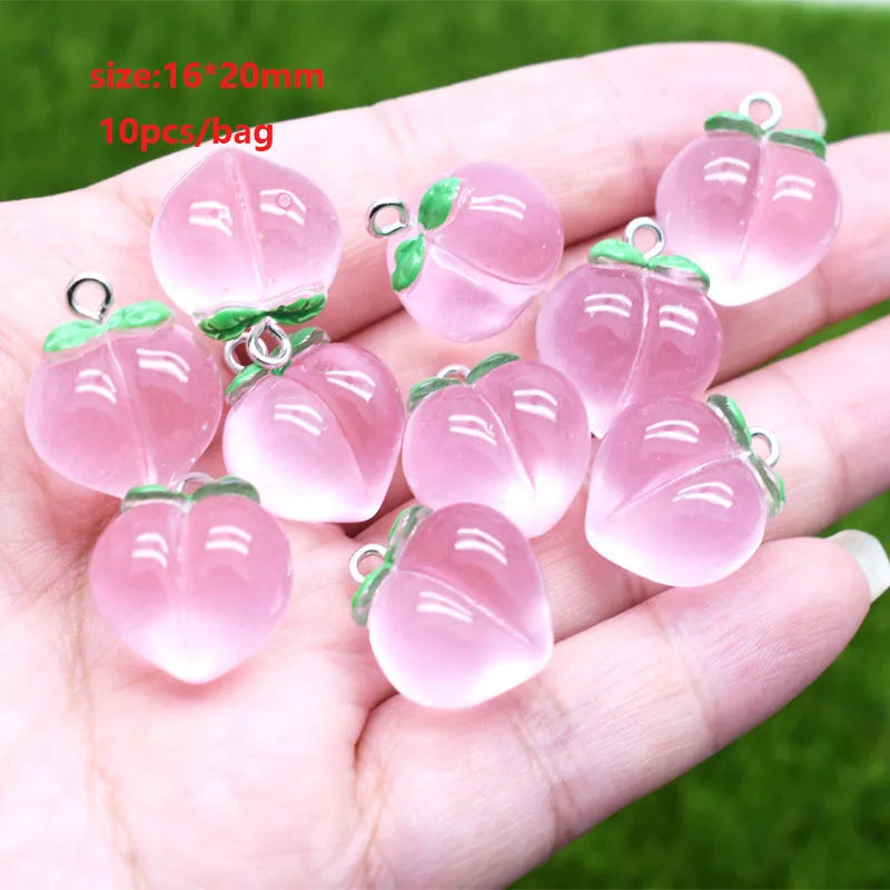 Ten pink translucent sunflower charms for jewelry making are displayed in a person's hand.