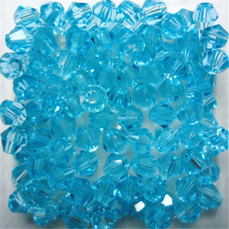 A pile of bright blue faceted glass bicone beads for jewelry making.