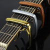 Close-up of an aluminum alloy quick-change guitar capo with wooden neck and strings.