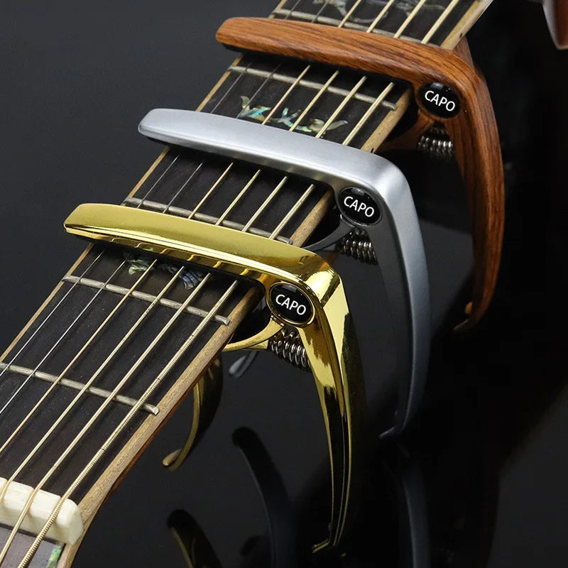 Close-up of an aluminum alloy quick-change guitar capo with wooden neck and strings.