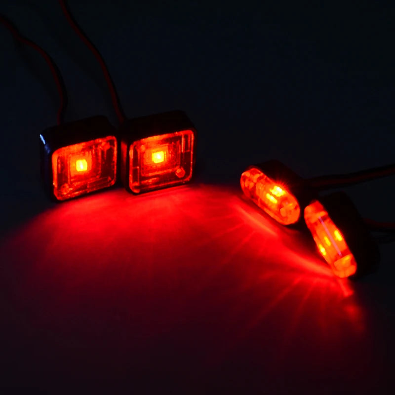 Two bright red LED warning lights illuminate a dark surface, casting beams of light.