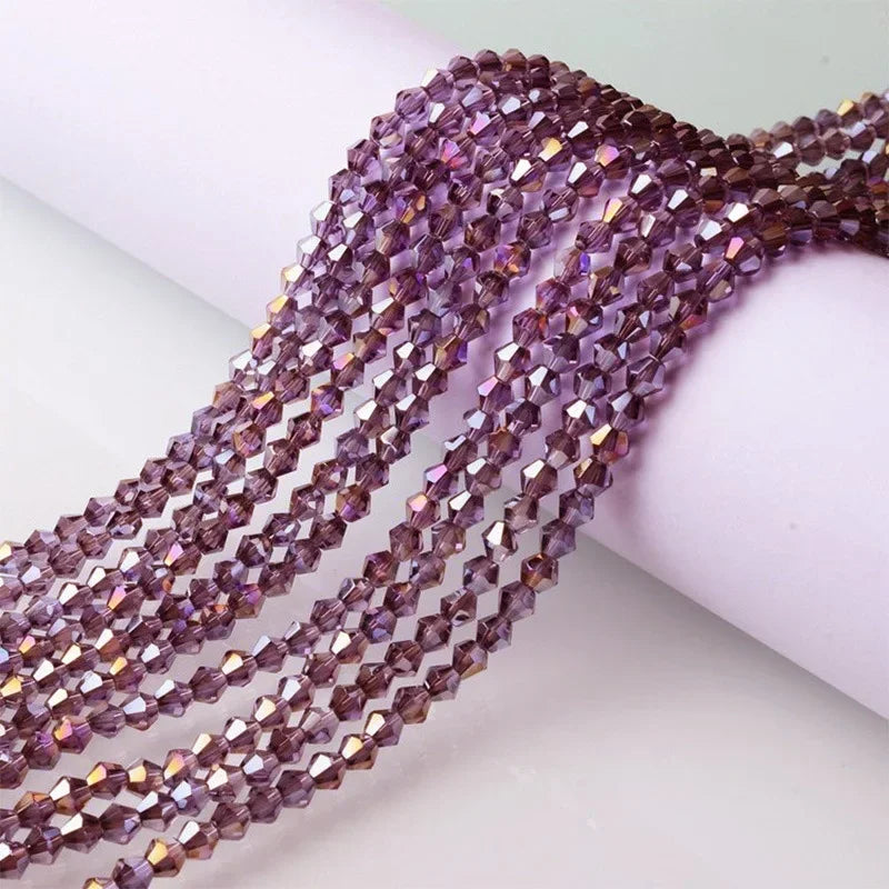 A close-up of purple and pink faceted glass crystal beads strung together for jewelry making.