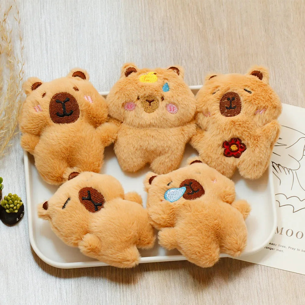 Five fluffy, light brown capybara plush toys arranged on a white plate.