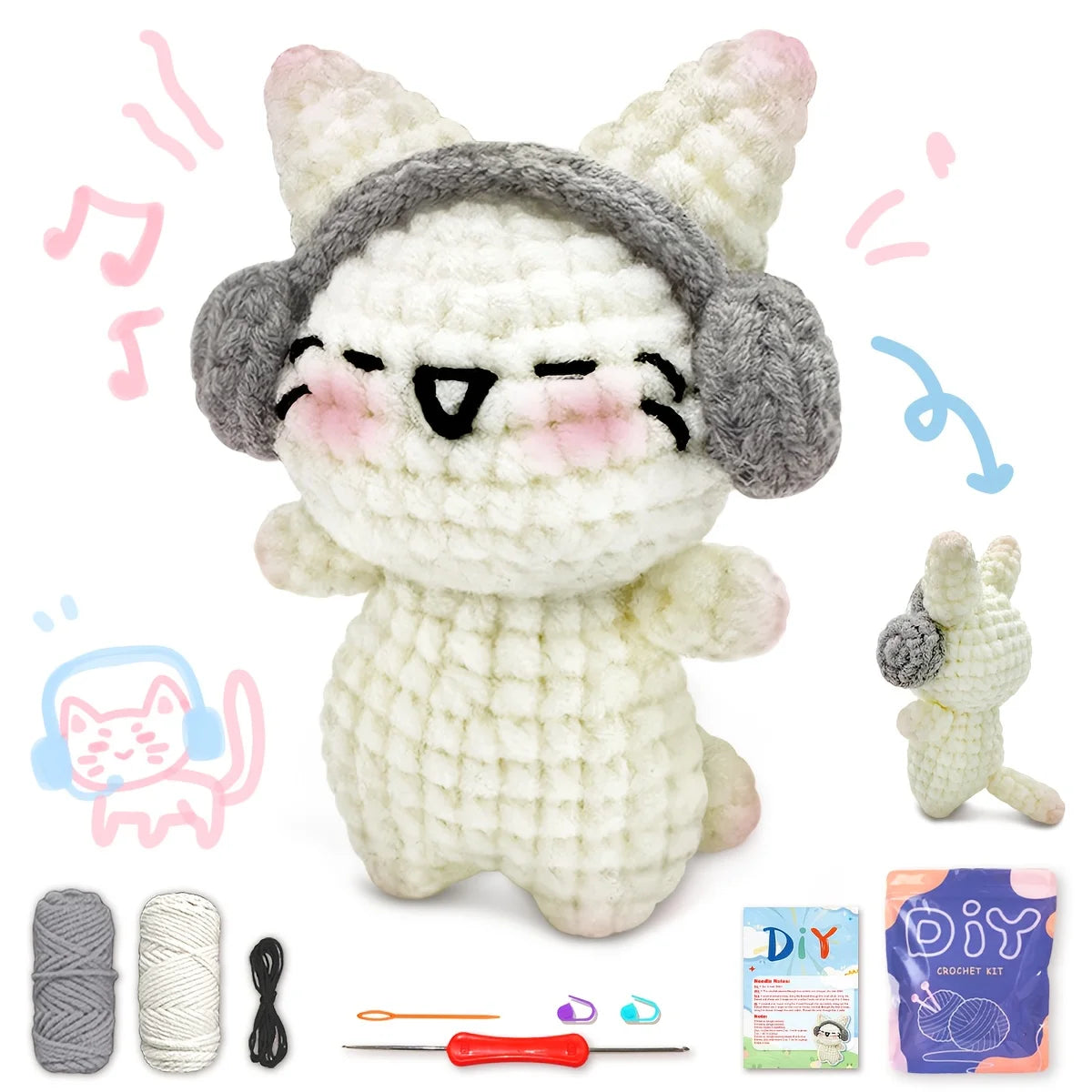 A handmade white and gray kitten crochet toy with a knitted hat, along with yarn and tools for crafting.