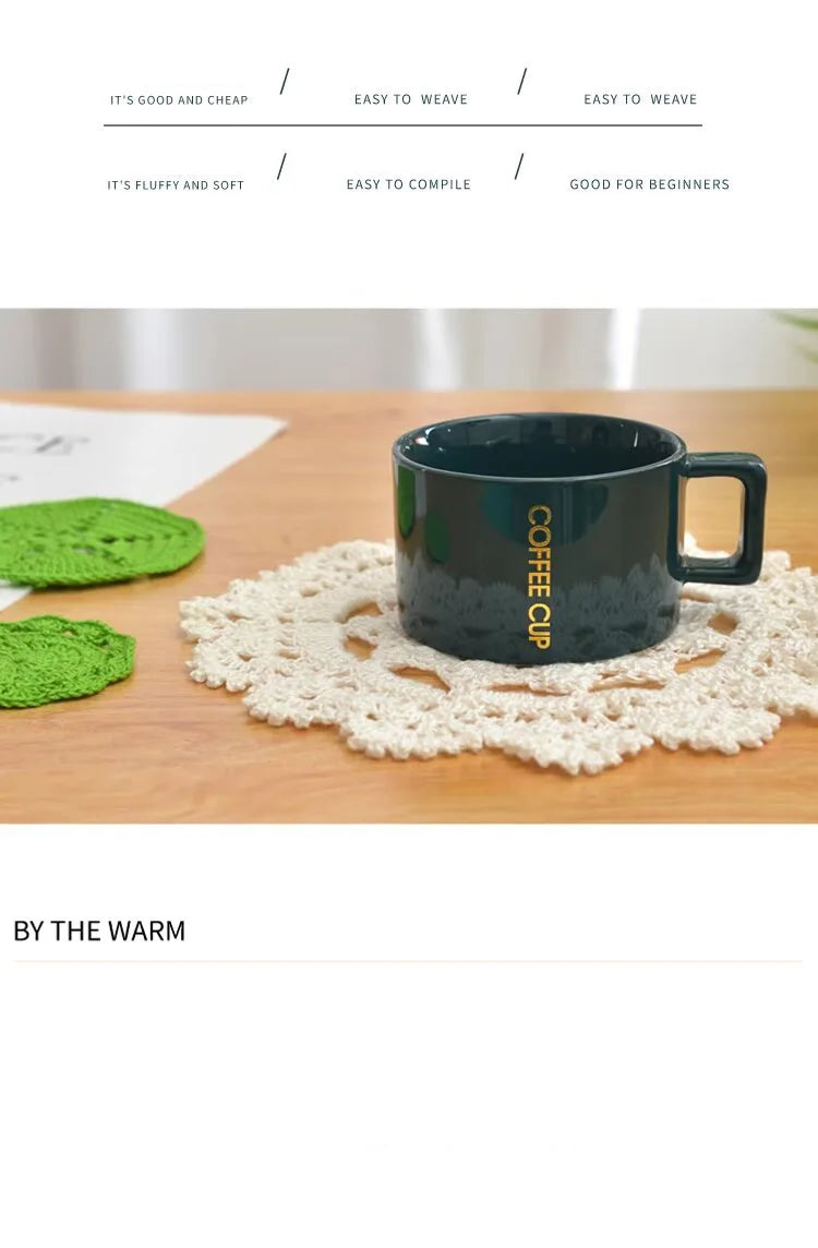 A dark ceramic coffee cup sits on a light wooden surface next to a white crocheted doily.