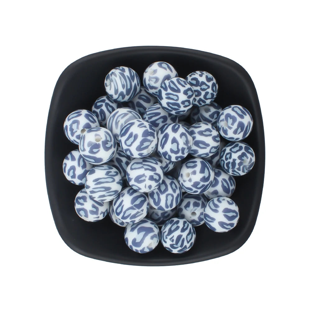 A bowl filled with small, round silicone beads featuring a blue and white leopard print pattern.