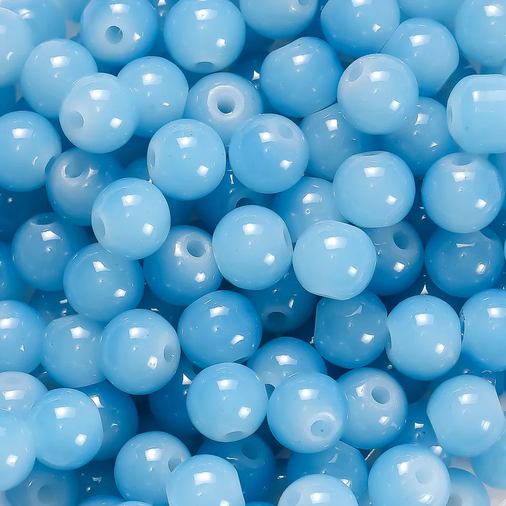 A close-up view of small, round, light blue glass beads for DIY jewelry making.