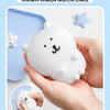 A hand holds a white silicone bear lamp with a smiling face, next to small checkered star shapes.
