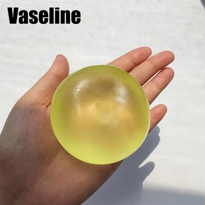 A hand holds a translucent yellow Vaseline fidget ball for stress relief.