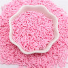 Pink polymer clay slice sprinkles poured into a white dish on a pink surface