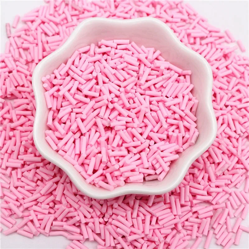Pink polymer clay slice sprinkles poured into a white dish on a pink surface