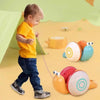 A toddler is playing with a yellow musical pull-along snail toy featuring colorful rolling spheres.