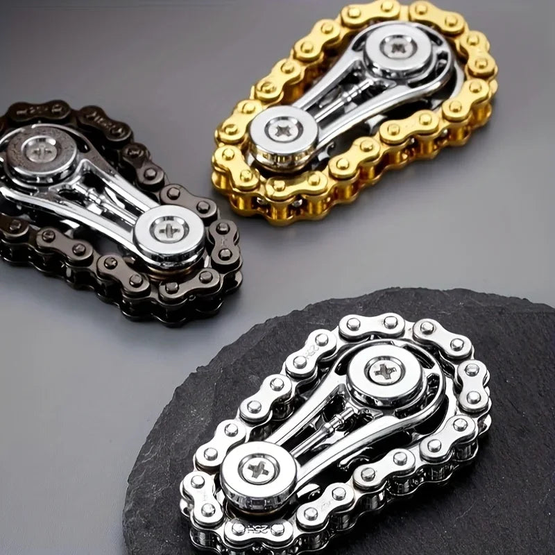A close-up view of a silver metal fidget spinner with a gold-colored textured ring, displayed on a dark surface.