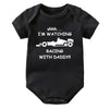 Black knitted baby romper with white text that reads Shhh I'm watching I'm watching racing with daddy
