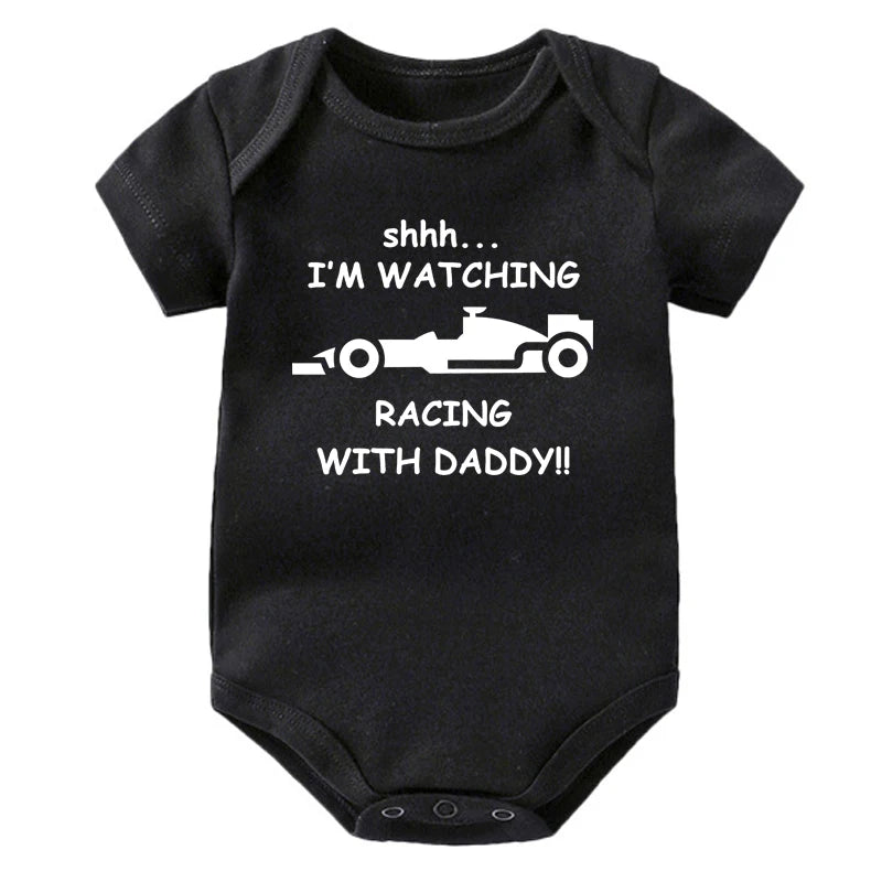 Black knitted baby romper with white text that reads Shhh I'm watching I'm watching racing with daddy