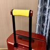 A close-up of a red suitcase handle with a yellow cushioned grip and black frame.