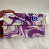 A rectangular purple and white marbled butter stick fidget toy is shown against a white fluffy background.