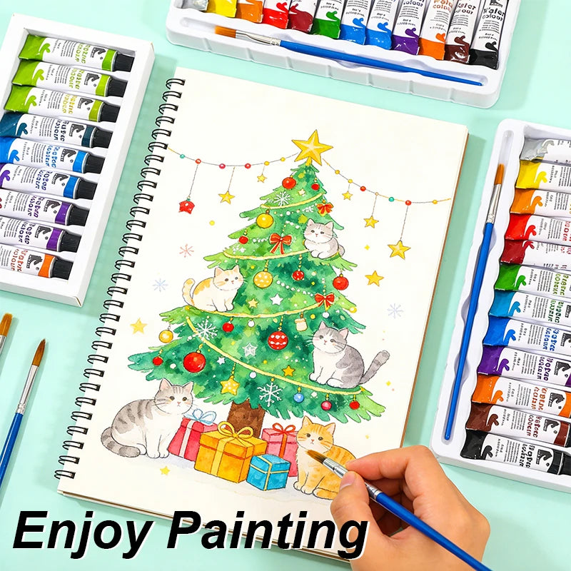 A set of 12-color acrylic, watercolor, and glass paints is displayed alongside a notebook featuring a Christmas tree drawing.