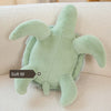 A light green sea turtle plush toy resting on a white textured surface.
