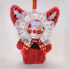 A red plush doll with white facial features and a large white frill, hanging from a silver ring.