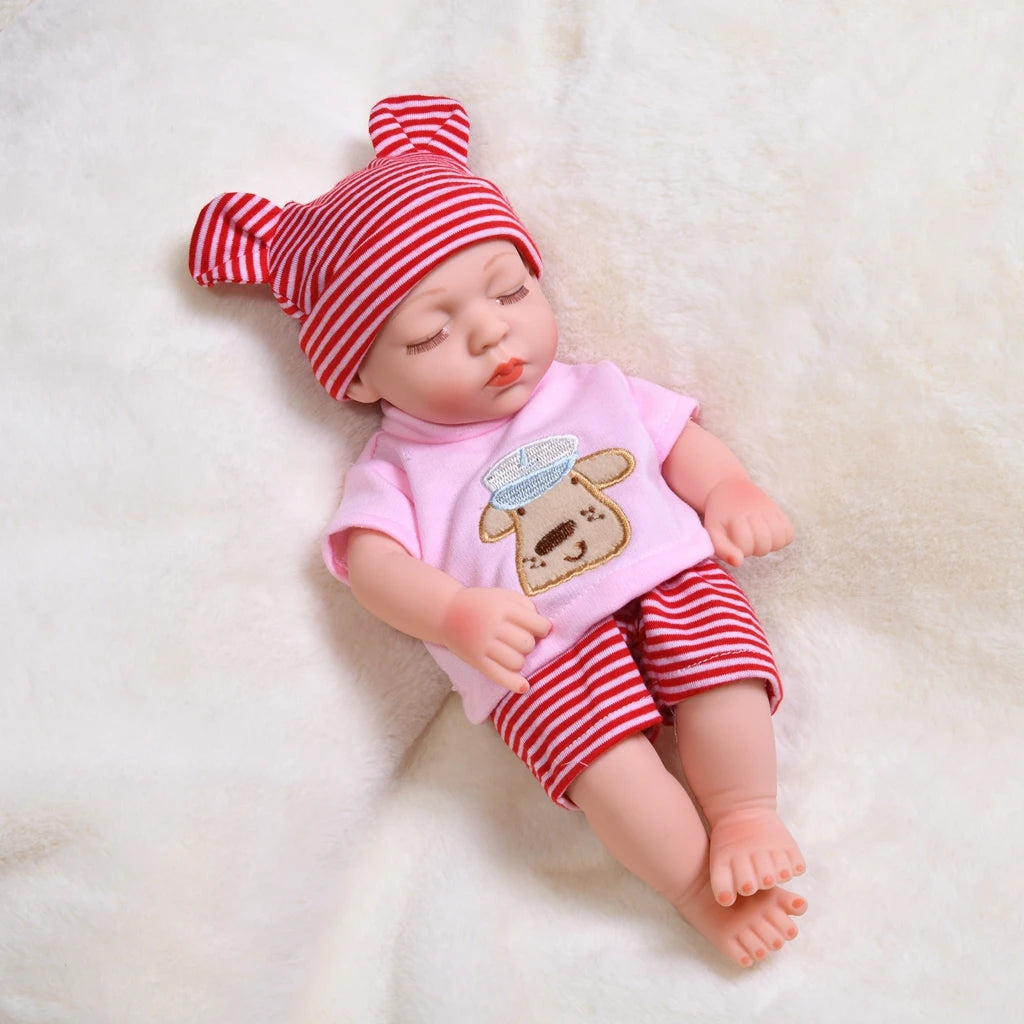 A lifelike soft vinyl reborn doll with a pink outfit and a red and white striped hat lying on a white fur surface.