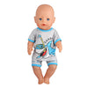 A baby doll wearing a gray shirt with a shark graphic and blue shorts.