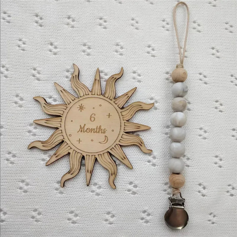 A wooden sun-shaped bead pacifier clip with a silicone teether on a natural twine string.
