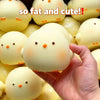 A hand holds a yellow squishy toy shaped like a chick, surrounded by similar toys.