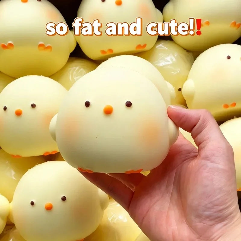 A hand holds a yellow squishy toy shaped like a chick, surrounded by similar toys.