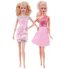 Deux poupées de mode, une blonde et une platine blonde, portant des robes roses scintillantes.