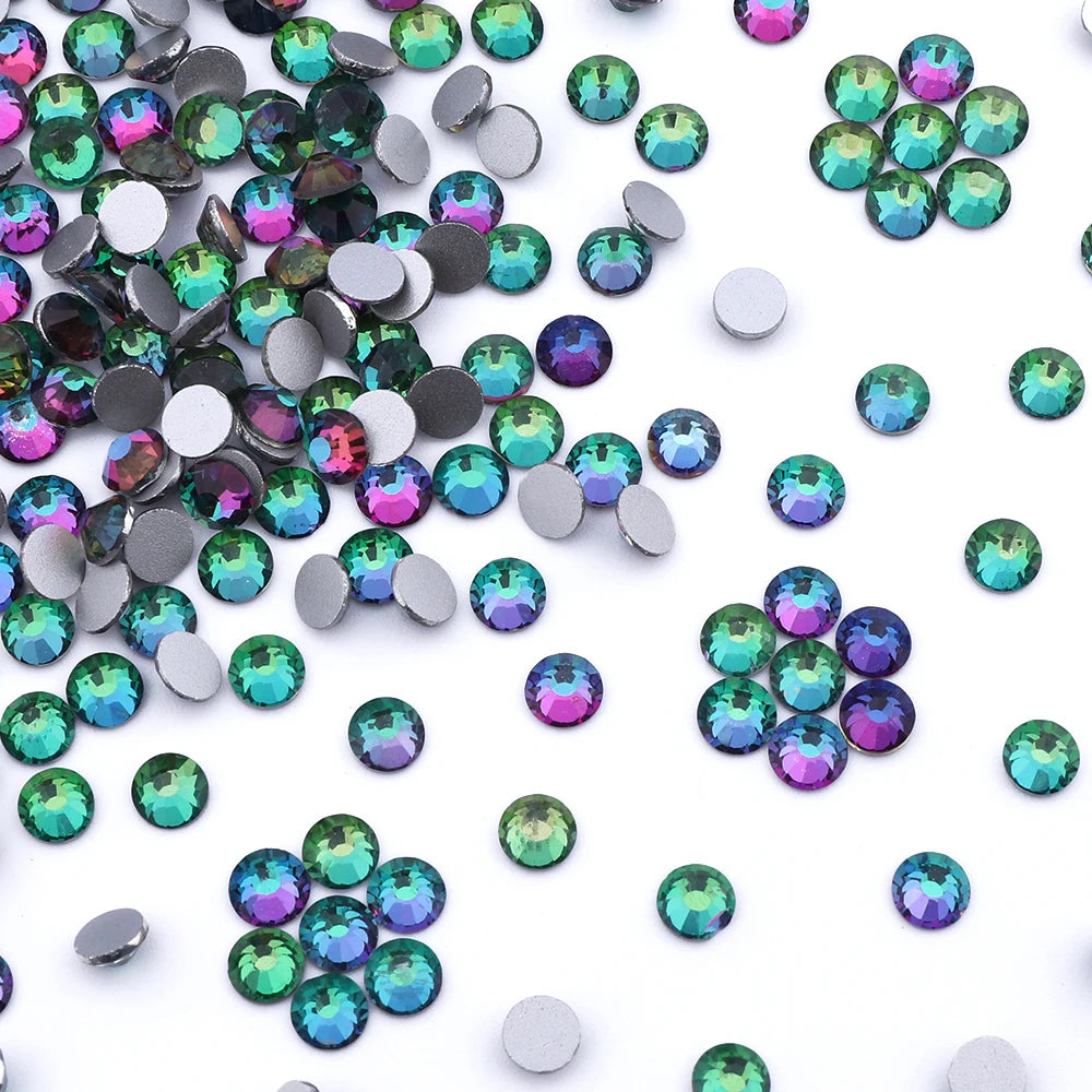 A collection of iridescent green and purple glass crystal flatback rhinestones for nail art and crafts.