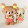 A plush toy of a brown bear with pink and green strawberry accents.