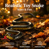 Realistic toy snake prop with a head and body lying on autumn leaves.