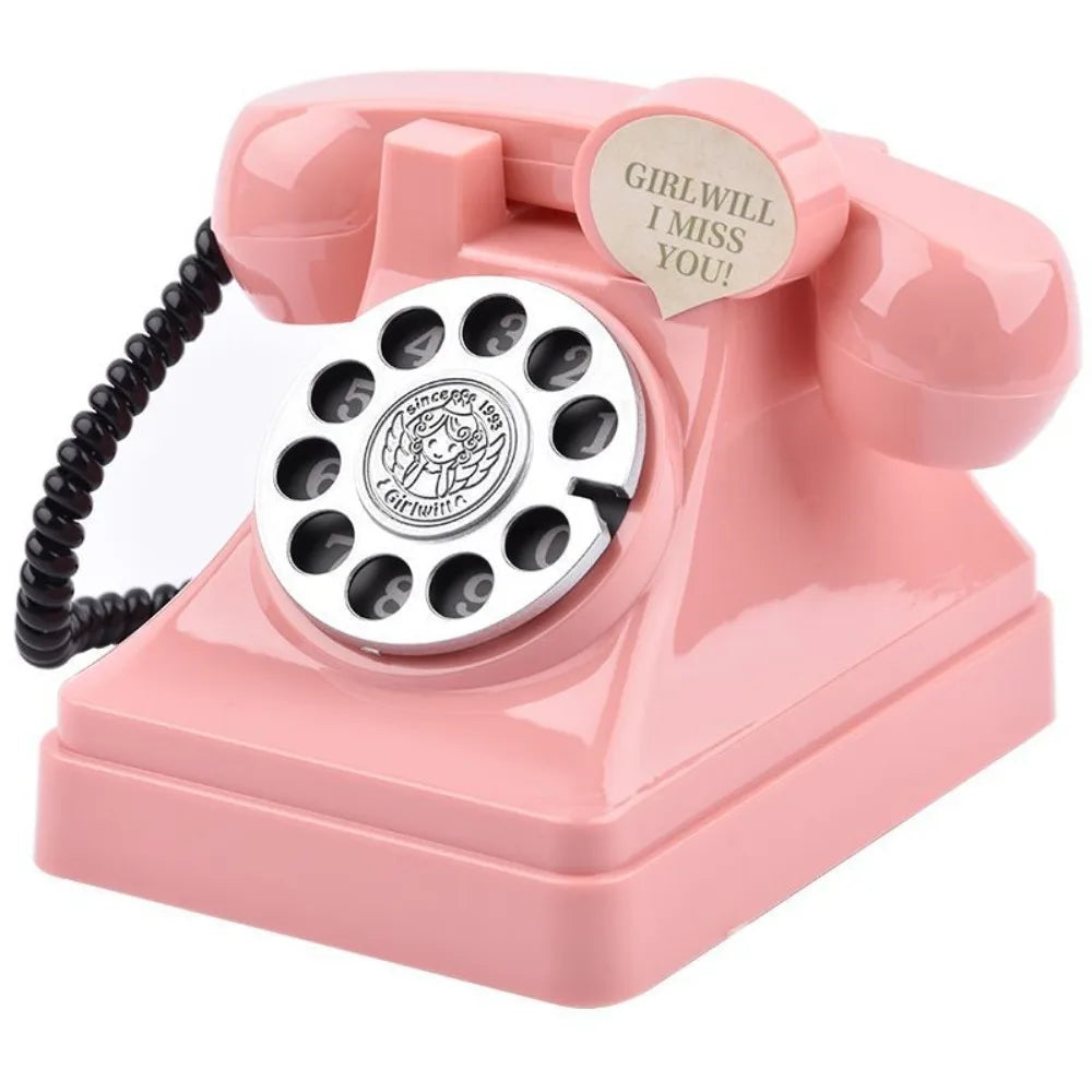 A pink vintage rotary telephone piggy bank with a circular dial and a tag that reads I miss you.