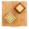 A square crochet piece featuring yellow, white, and green yarn is displayed on a wooden board with pins and a stand.