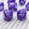 A set of purple resin dice featuring a black kitten design on the faces, displayed on white paper.